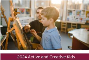 Image of child painting on an easel with man watching on as a teacher